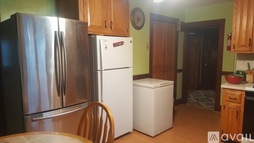 A kitchen with a stainless steel refrigerator, a white dishwasher, and wooden cabinets.