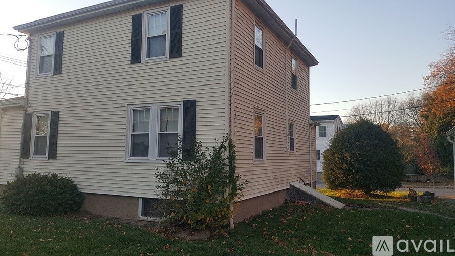 A two-story house with a beige siding and black shutters.