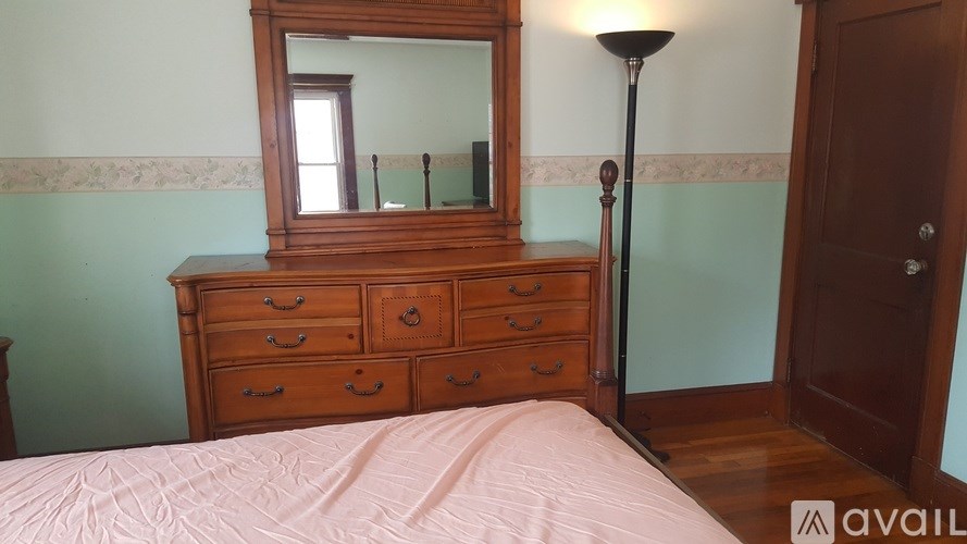 A bedroom with a bed, dresser, and mirror.