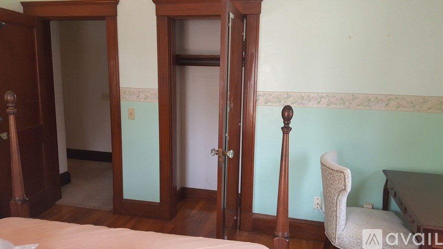 A room with a bed, a chair, and a door.