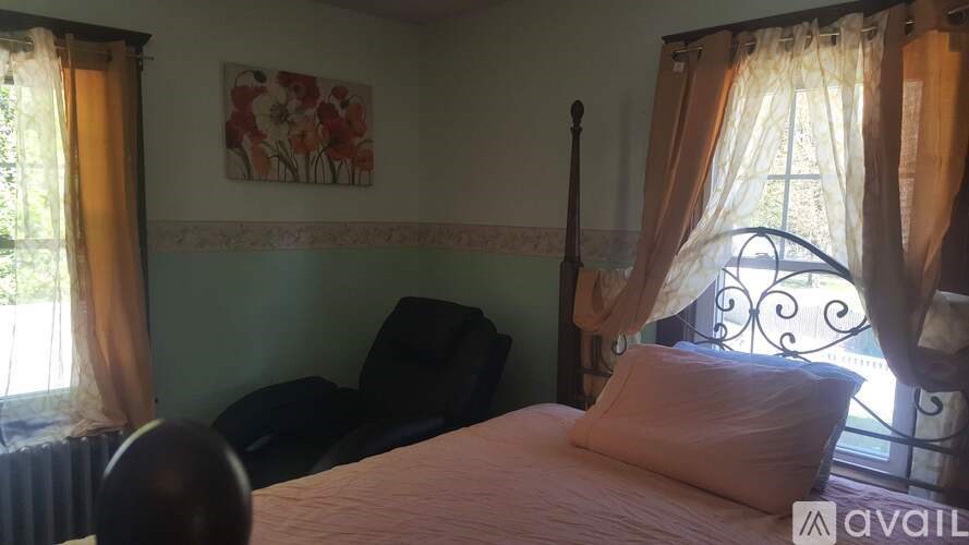 A bedroom with a bed, a chair, and a window with curtains.