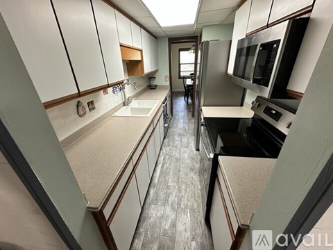 A kitchen with white cabinets and a black fridge.