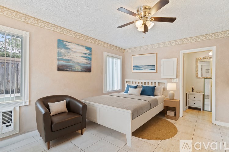 A bedroom with a bed, chair, and a ceiling fan.