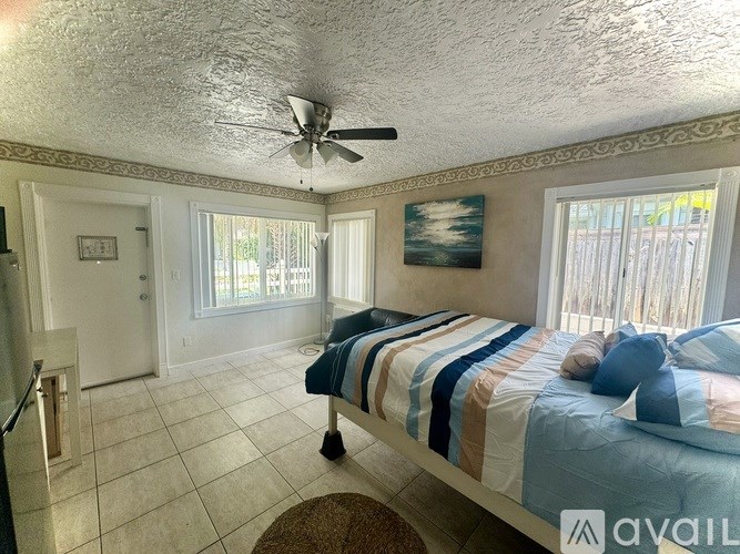 A bedroom with a bed, a ceiling fan, and a painting on the wall.