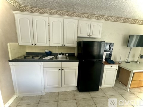 A kitchen with white cabinets and a black refrigerator.
