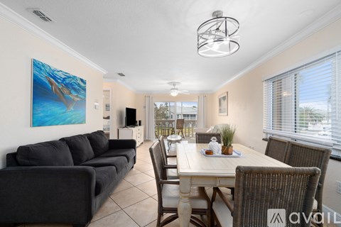 A living room with a grey couch and a dining table with chairs.