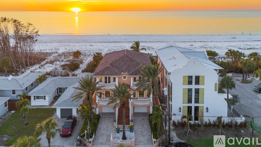 A house with a sunset in the background and a car parked in the driveway.