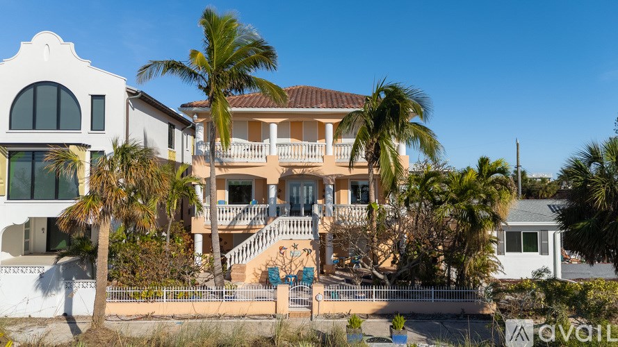 A house with a balcony and a palm tree in front.