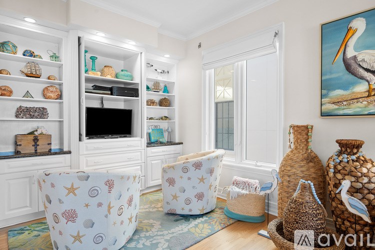 A living room with a TV, a chair, and a painting of a stork.
