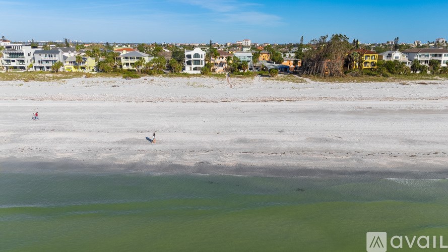 Two people are walking on a beach near the water.