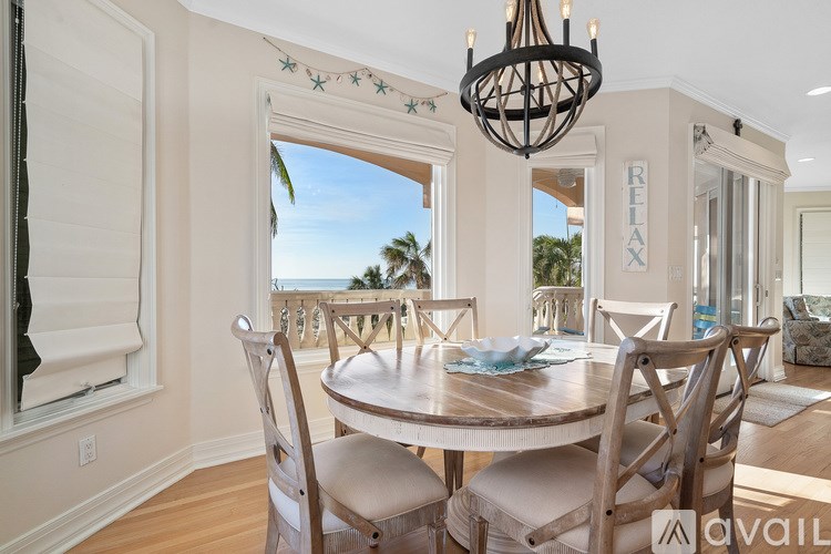 A dining room with a table set for four and a chandelier hanging from the ceiling.