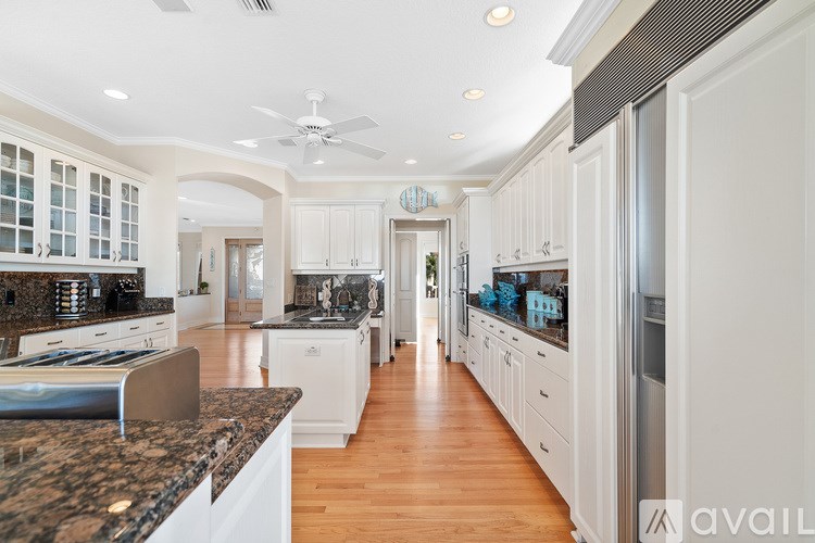 A kitchen with white cabinets and a marble countertop.