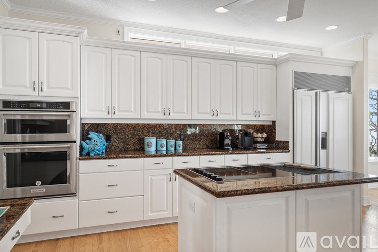 A kitchen with white cabinets and a granite countertop.