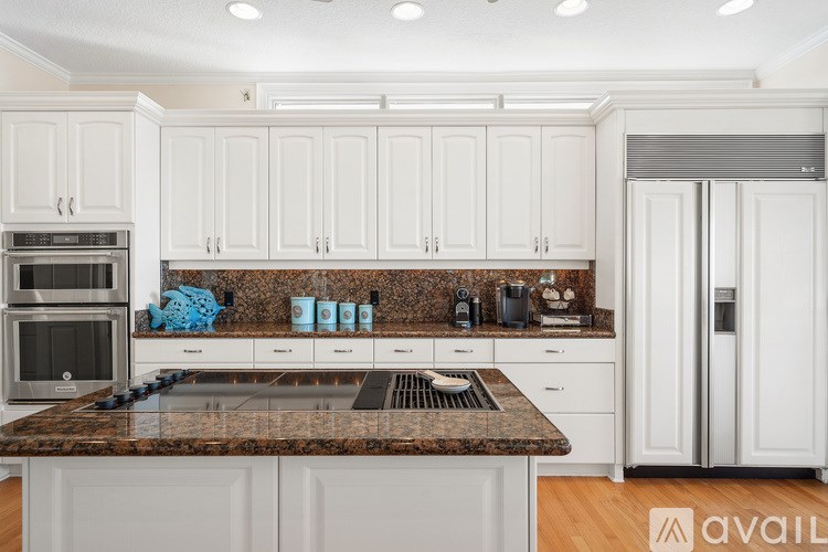 A kitchen with white cabinets and a granite countertop.