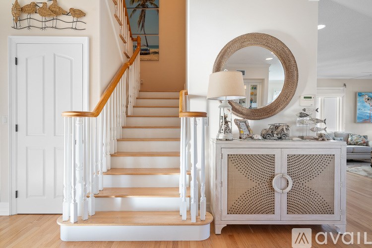 A staircase with a wooden banister and a round mirror above a cabinet.