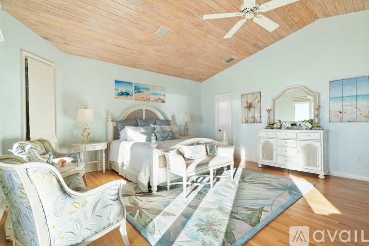 A bedroom with a bed, chair, and a painting on the wall.