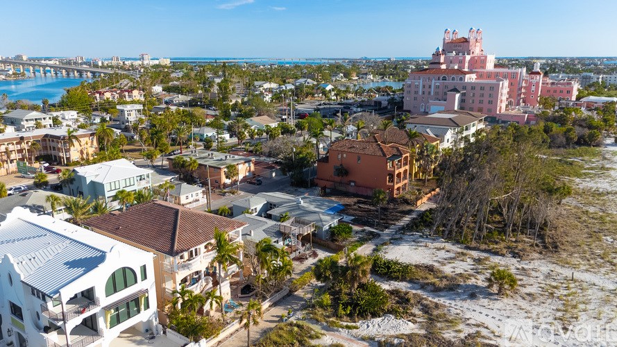 A bird's eye view of a coastal town with a large pink building in the center.