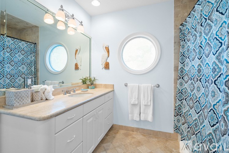 A bathroom with a white counter and a blue and white shower curtain.