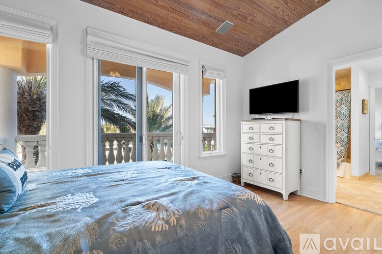 A bedroom with a bed, dresser, and sliding glass doors.
