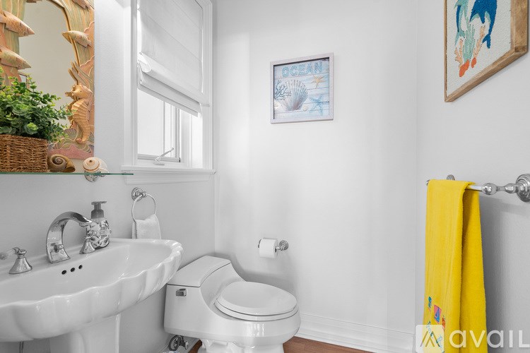 A white bathroom with a toilet, sink, and a yellow towel.