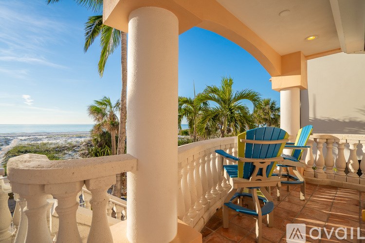 A balcony with a table and chairs overlooking a beach.