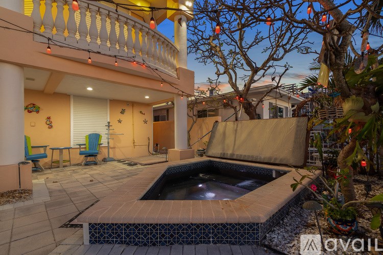 A hot tub is surrounded by a tiled patio and a balcony with a yellow railing.