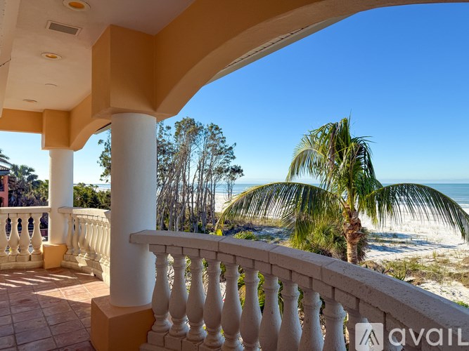 A balcony with a view of the beach and palm trees.
