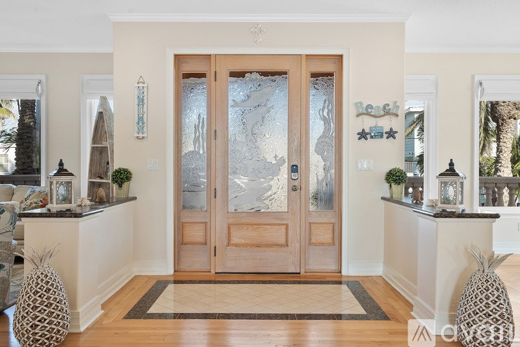 A wooden double door with frosted glass panels is the centerpiece of a foyer with a rug and two pinecone decorations.