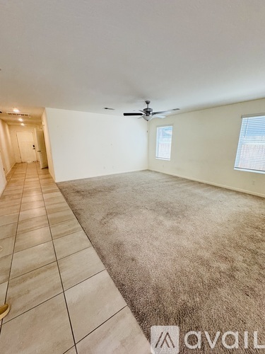 A spacious room with a carpeted floor and a ceiling fan.