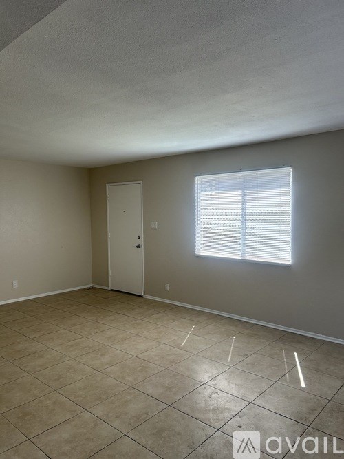 Empty room with tile flooring and a window with blinds.