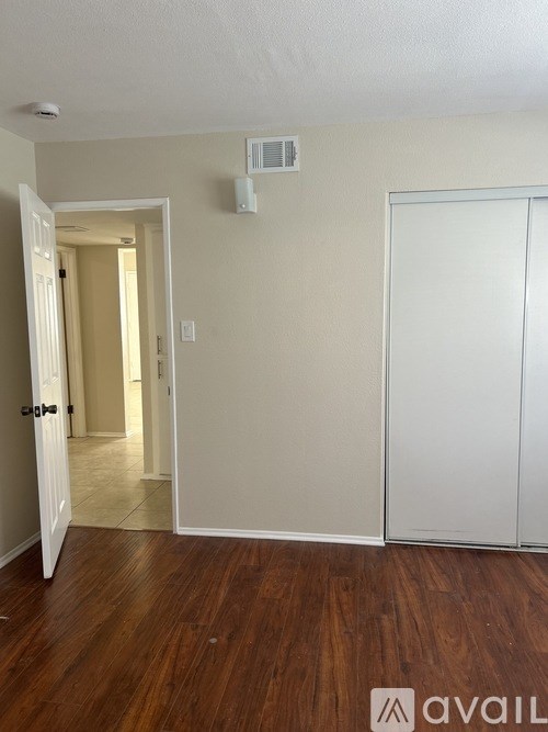 A room with a white door and a white wall with a vent.