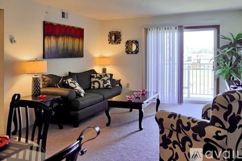 A living room with a black couch and a painting on the wall.