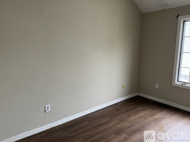 A room with a window and wooden flooring is available for rent.