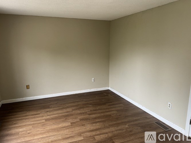 A room with wooden flooring and beige walls.