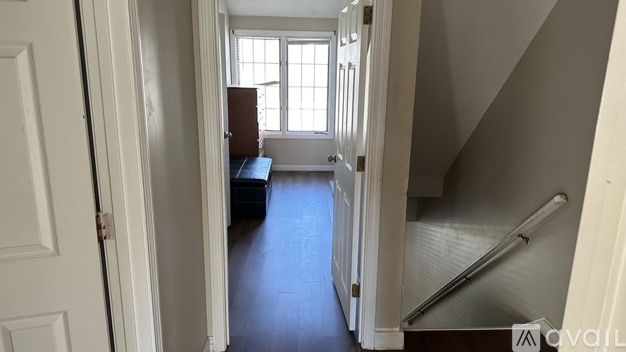 A hallway with a door on the left and a window on the right.