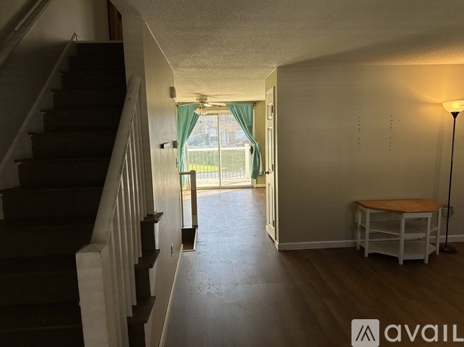 A hallway with a staircase on the left and a table with a lamp on the right.