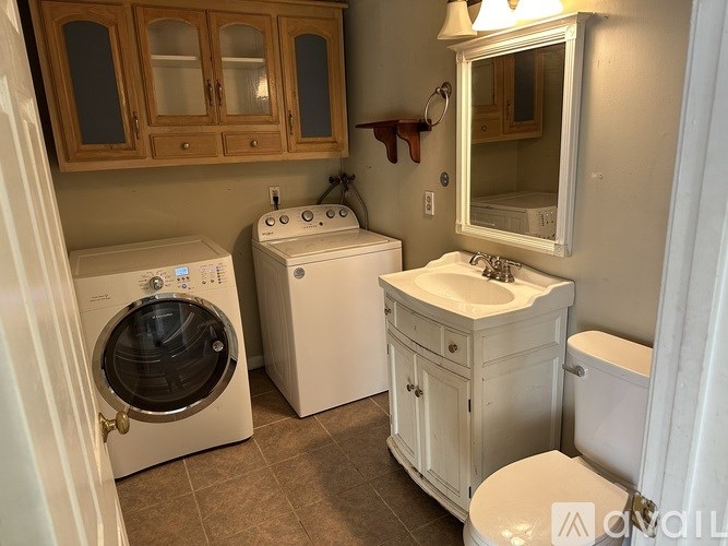 A small laundry room with a washer and dryer, a sink, and a toilet.