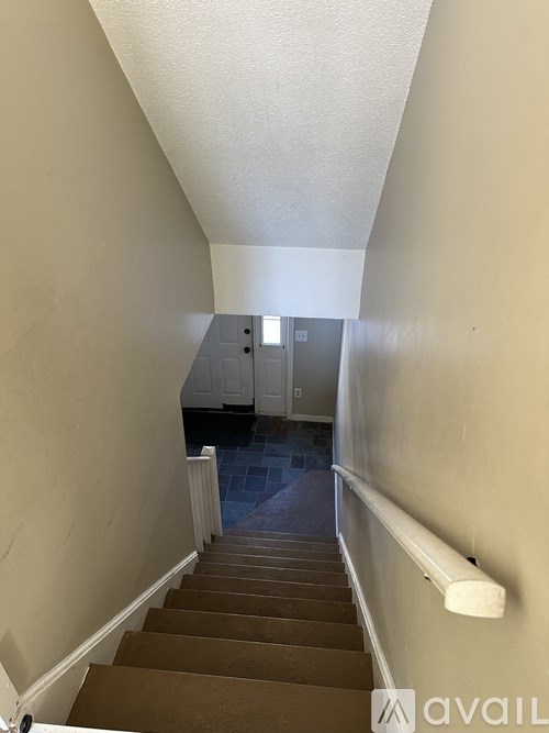 A stairway with a carpeted floor and a white wall on the side.