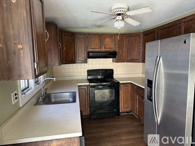 A kitchen with a stove, sink, and refrigerator.