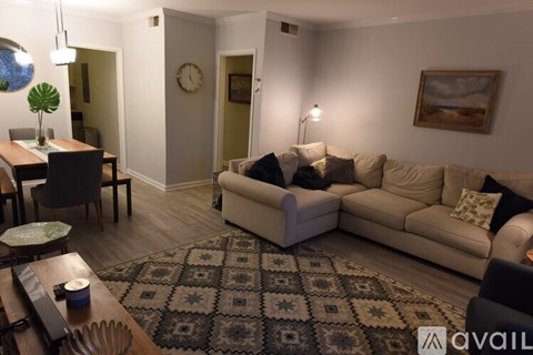 A living room with a beige couch and a patterned rug.