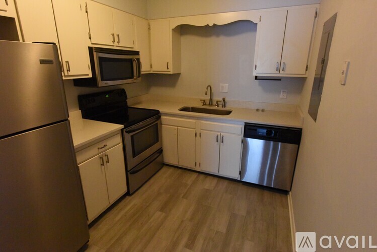 A kitchen with a refrigerator, microwave, oven, and sink.