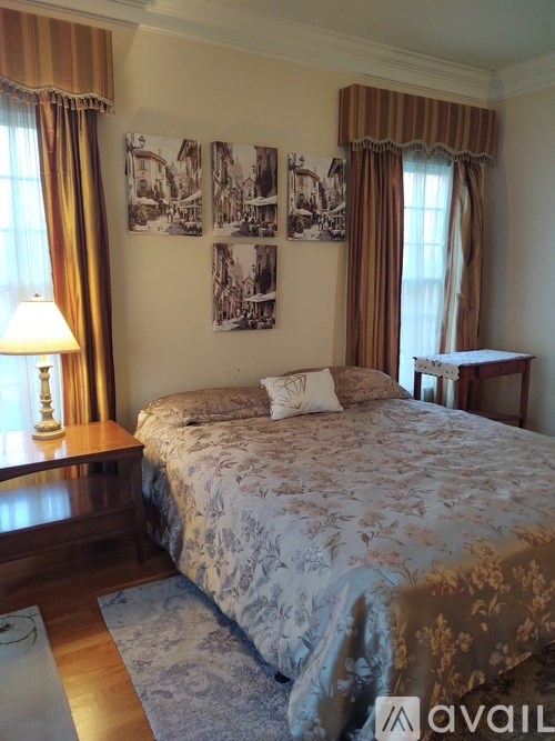 A bedroom with a large bed and pictures on the wall.