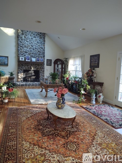 A living room with a stone fireplace and a rug on the floor.