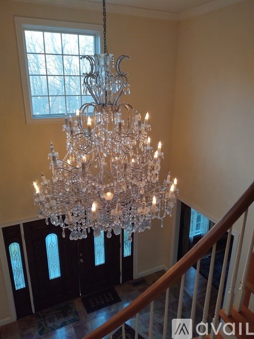 A large chandelier hangs from the ceiling in a room with a staircase.