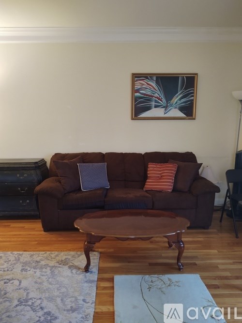 A brown couch with a blue rug and a brown coffee table in front of it.