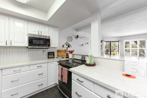 A kitchen with white cabinets and a black stove top.