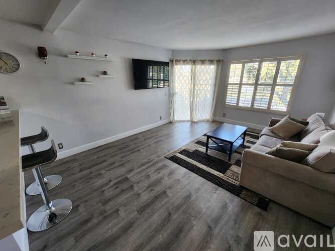 A living room with a couch, chair, and a clock on the wall.