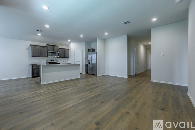 A spacious kitchen and living room with wooden floors and white walls.