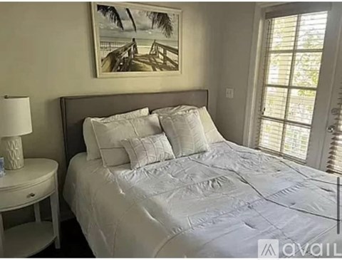 A bedroom with a large bed and a painting of a beach scene on the wall.