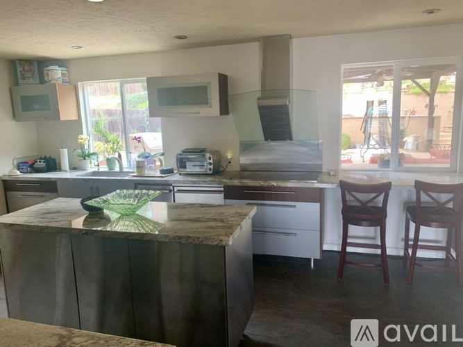 A kitchen with a granite countertop and wooden chairs.